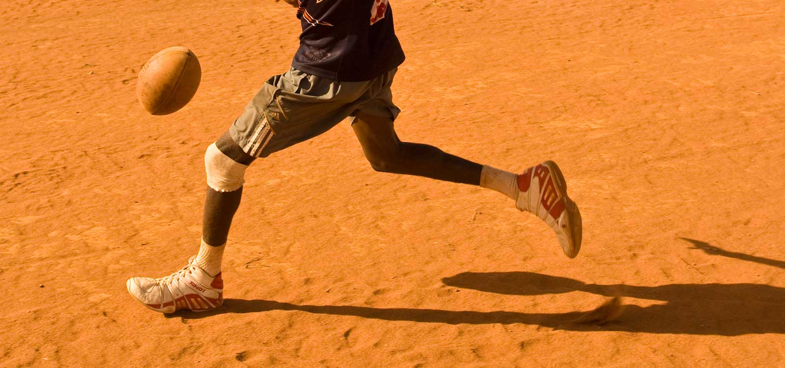 image of AARONTAIT COPYRIGHTED 2014 5312 EDITORIAL DOCUMENTARY PHOTOGRAPHER PAPUNYA NORTHERN TERRITORY AUSTRALIA LANDSCAPE LIFE PEOPLE ART INDIGENOUS PINTUPI LURITJA PAPUNYA TULA FOOTY BOOTS RUNNING RED CENTRE
